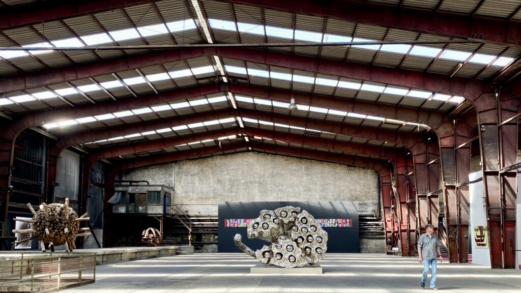 Eine große Fabrikhalle, in dereinge Skulpturen aufgestellt sind.