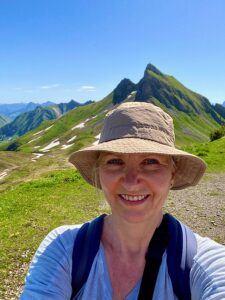 Frau mit Hut vor Alpenlandschaft