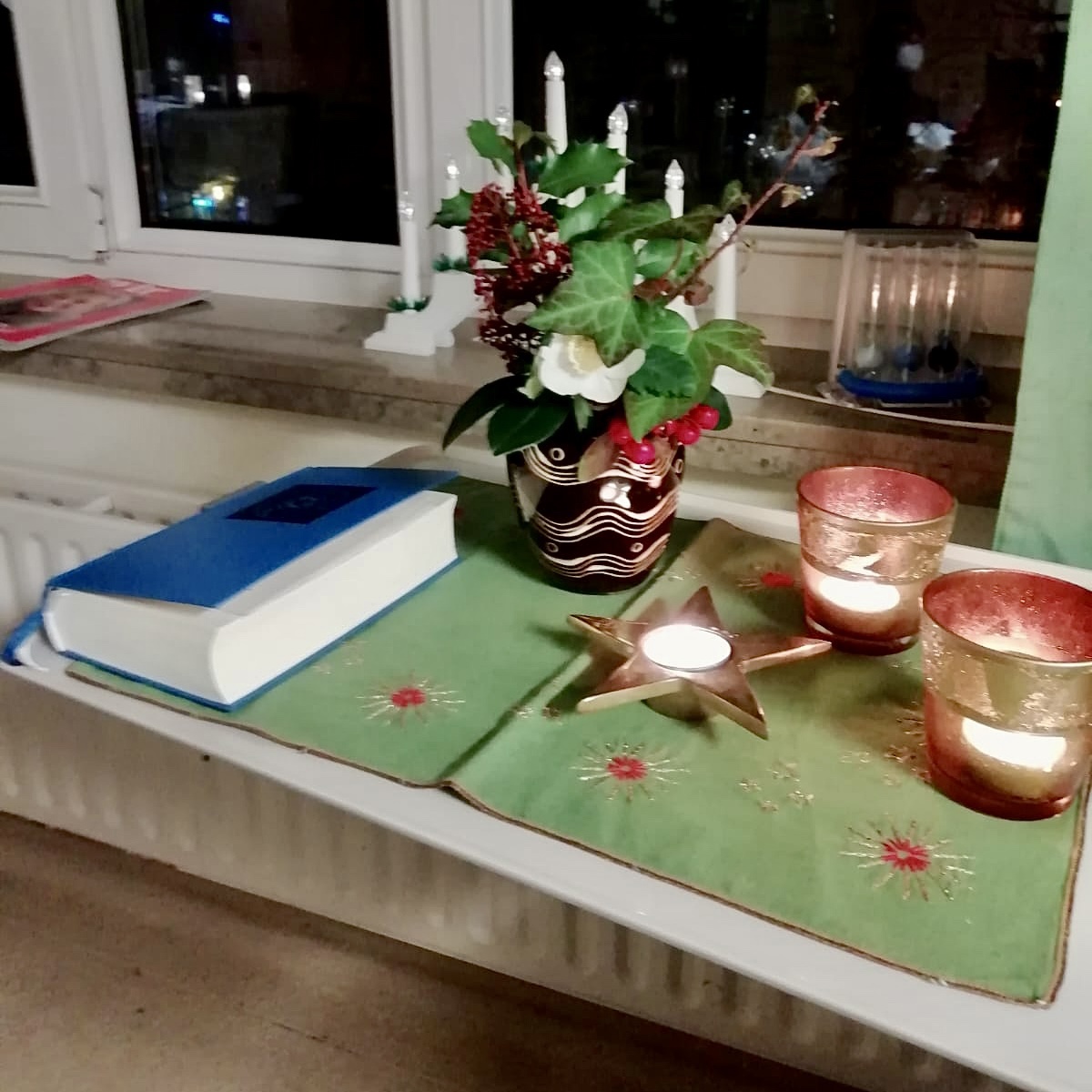 Kerzen, Blumen, Gesangbuch auf Weihnachtsdecke auf dem Nachttisch