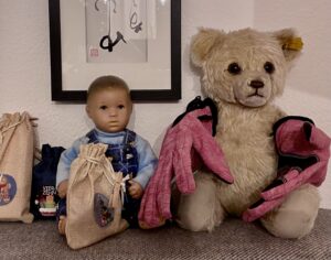 Ein Teddybär mit Fahrradhandschuhen und eine Puppe