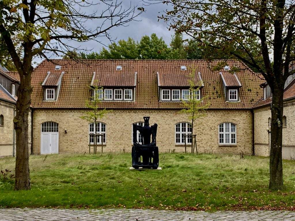 Haus, vor dem eine große schwarze Skulptur steht